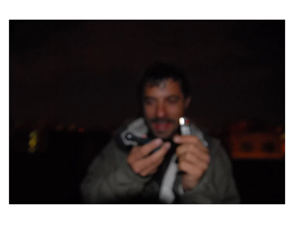 A blurry image of a figure emerging from the darkness holding a pipe and a lighter
