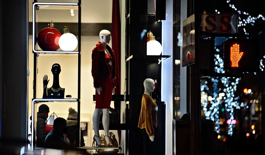 Shop windows mix with real life in silhouetted human figures, lights, and Christmas ornaments.