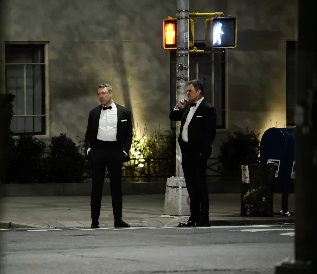 Two party attendees tipsy on the street after a good evening wearing tuxedos.